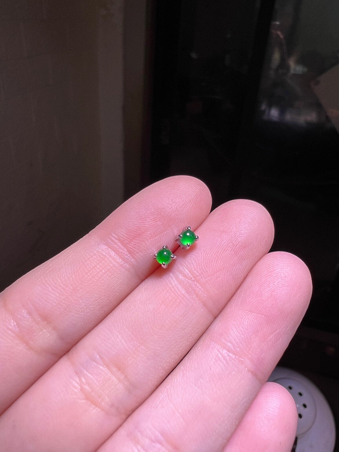 Green cabochon stud earring worn on a model ear lobe, small and close to the skin