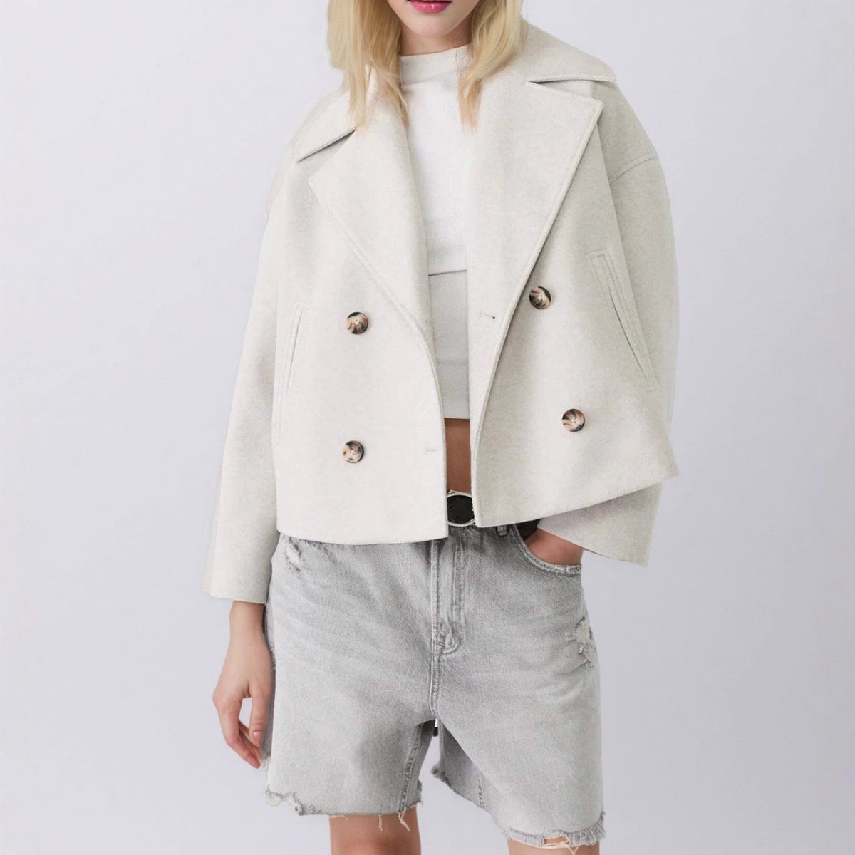 Black short double breasted wool coat worn open over a knit and grey shorts