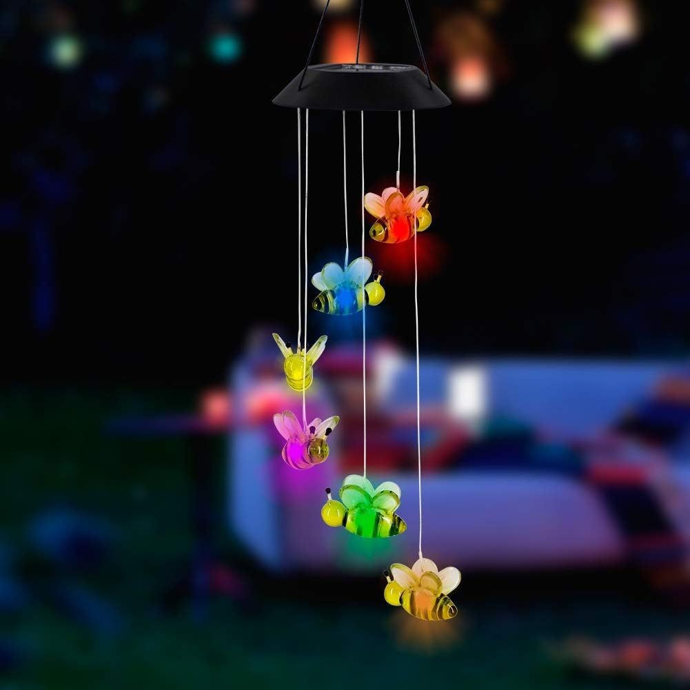 Bee LED figures glowing in several colors, hanging from a solar lamp head at night, black housing option