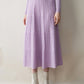 Woman wearing a lilac ribbed knit tiered midi skirt with cream ankle boots and a lilac knit top