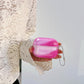 Green glow marble AirPods cover case held in hand against a black skirt