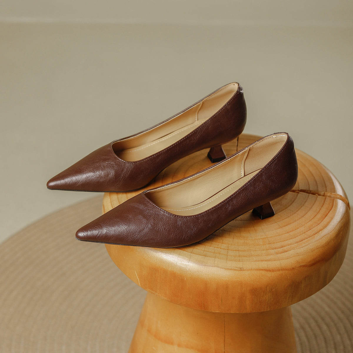 Pair of brown pointed toe pumps with a low flared heel on a wooden stool, Brown option, size 38