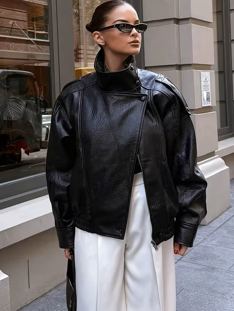 Woman in sunglasses wearing a black moto jacket with an asymmetric front zip and white trousers