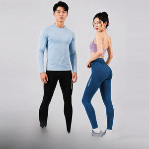 Man in black leggings and a light blue top standing beside a woman in dark blue high waist leggings