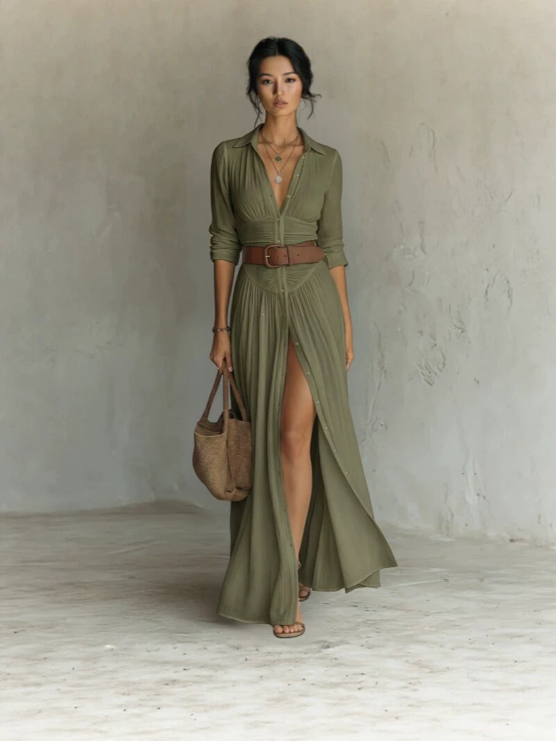 Woman in a dark green long shirt dress with collar, brown belt and a high front slit, full length front view