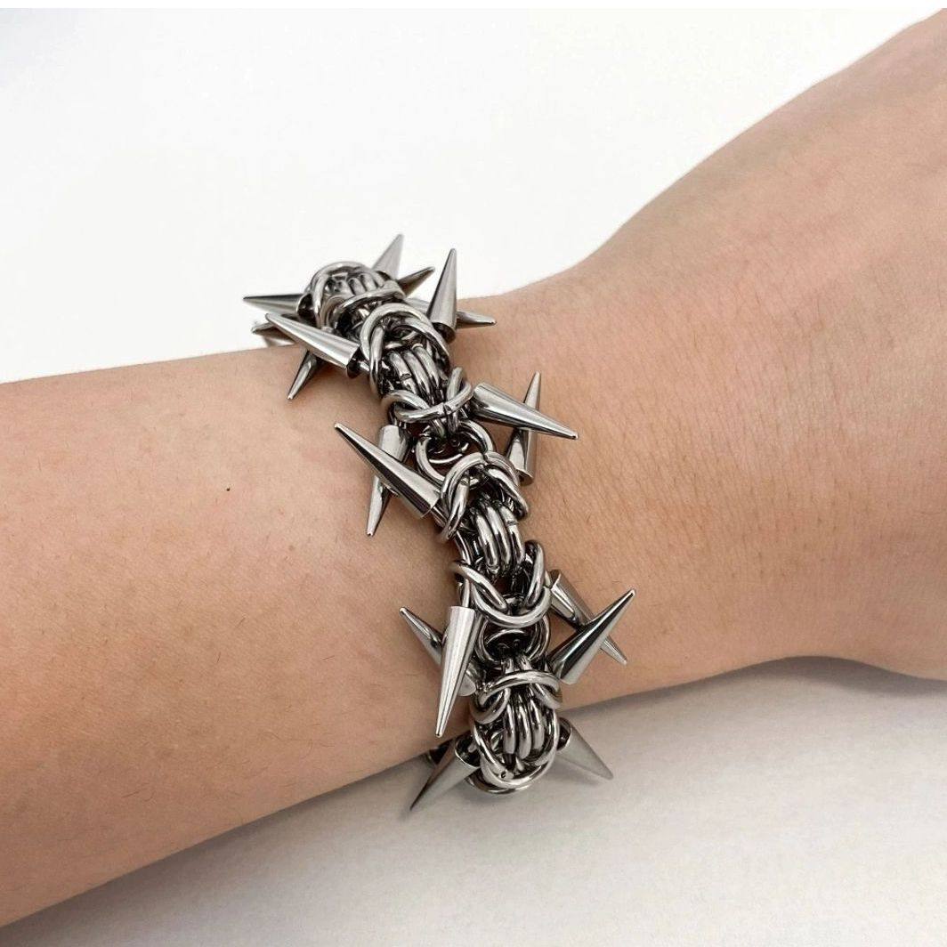 Silver tone cone spikes rising from a woven byzantine chainmail band