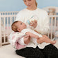 Baby nursing support pillow shown front on, cushioned wrap shape with soft printed cover