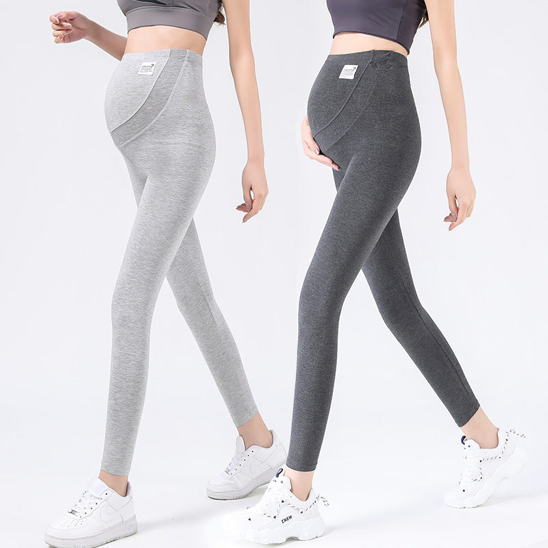 Two women in light gray and dark gray ankle length maternity leggings with belly panels, white trainers