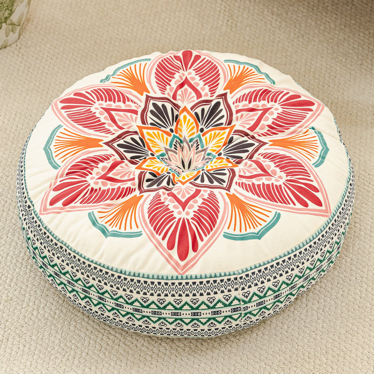 Round cushion with a coral, red and orange lotus print on a cream top and a teal woven border