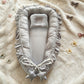 Baby nest with a small head pillow and a bow, measuring about 55 by 85 cm