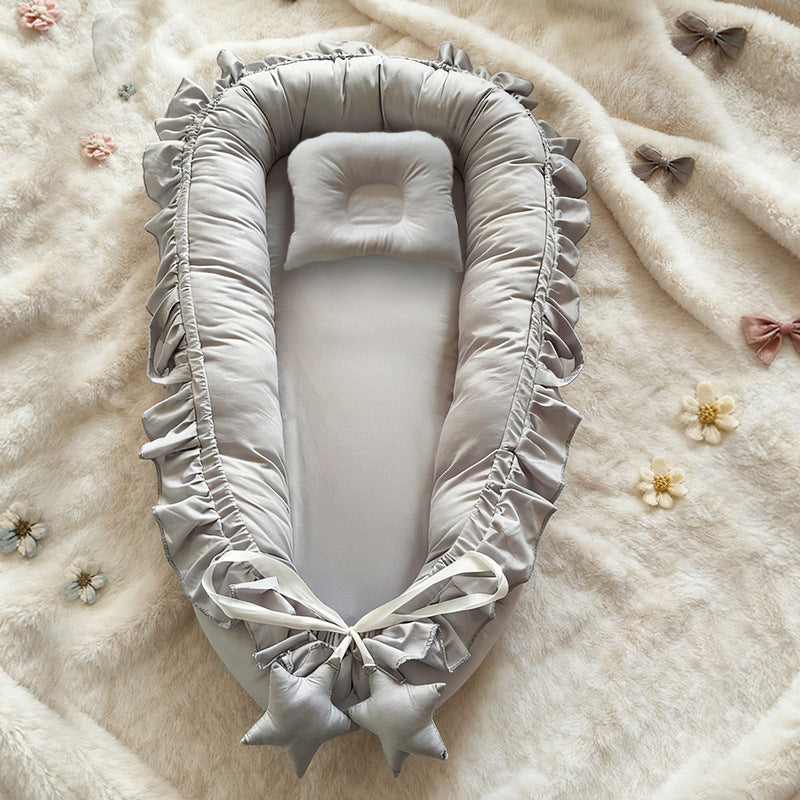 Baby nest with a small head pillow and a bow, measuring about 55 by 85 cm