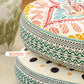 Close up of the side of stacked round print cushions showing a woven zigzag border and a polka dot design