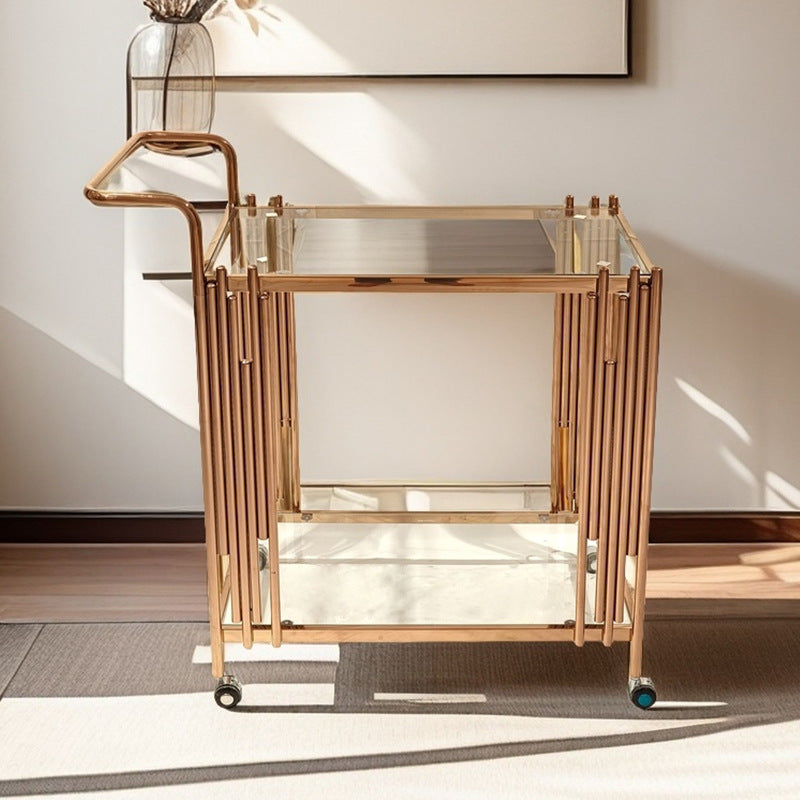 Two tier bar cart in gold toned steel with clear tempered glass tiers and a push handle