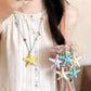 Yellow resin starfish cord necklace worn over a striped dress with a hand holding starfish pendants