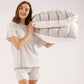 Woman holding two gray puff grid bed pillows against a plain studio backdrop