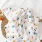Large cotton muslin gauze baby blanket laid out, showing the loose breathable weave and print