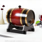 Wine red wooden barrel dispenser with gold bands and a wooden tap, wine glass alongside