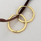 Hand holding one of the gold hoops between two fingers in daylight