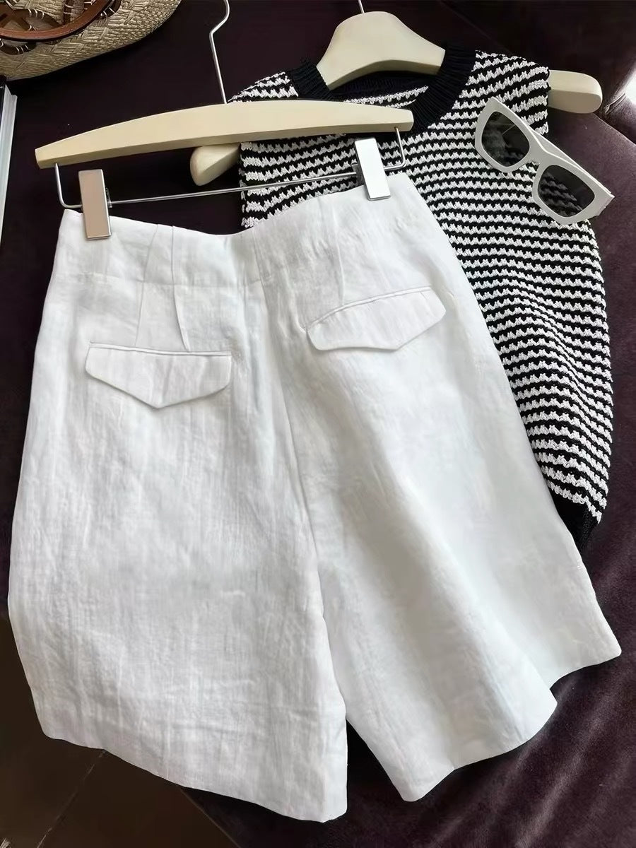 White linen shorts shown with straw bag striped knit top and sunglasses