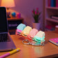 Pastel keycap clicker keychain glowing on a desk next to a laptop and lamp