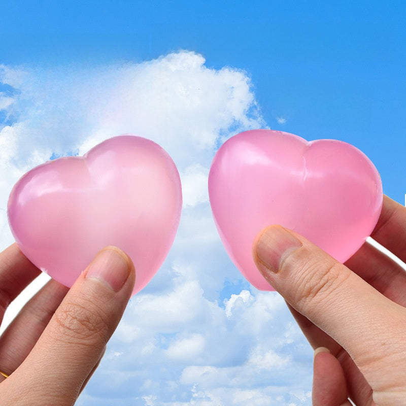Two frosted pink heart squeeze toys held up against a blue sky, light passing through them