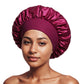 Woman wearing a burgundy satin bonnet with a ruffled crown and a wide matching elastic band