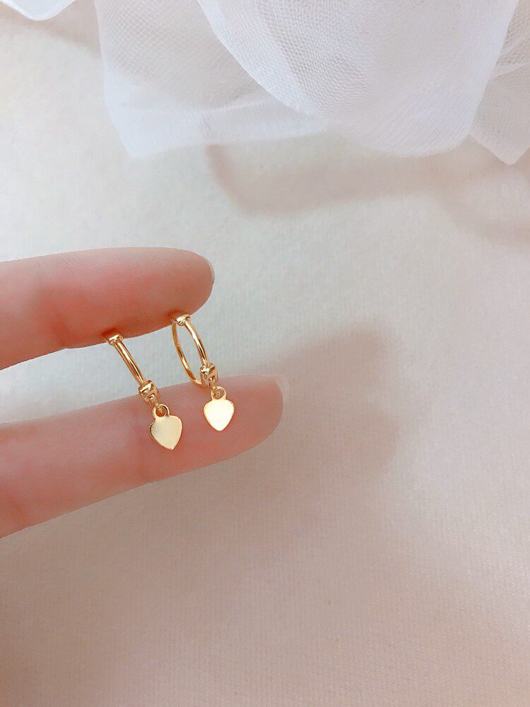 Heart ear cuff stacked with a small gold hoop in the lobe