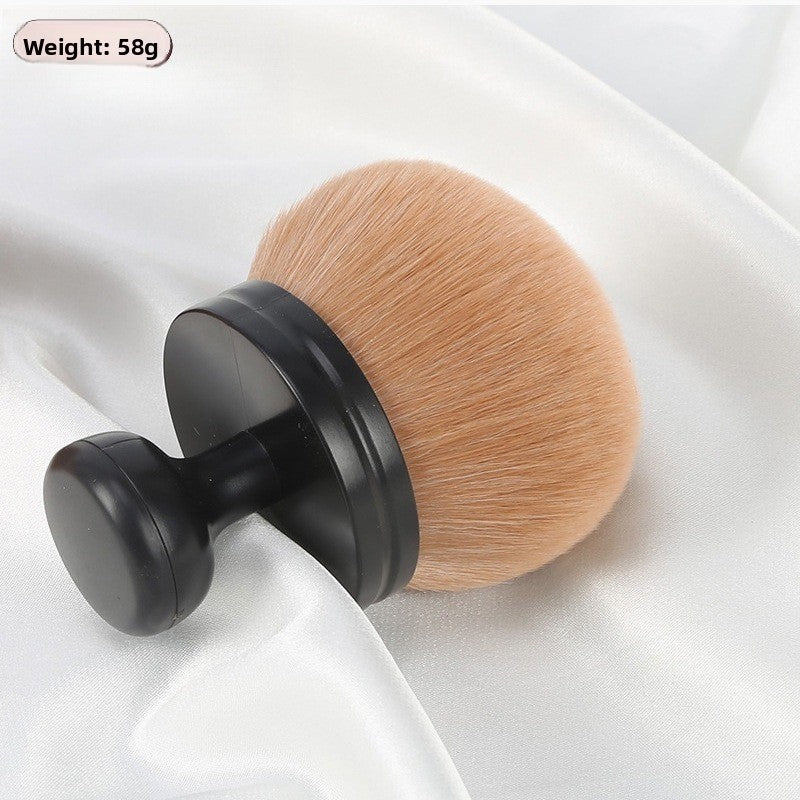 Black handle mushroom brush with brown bristles resting on white satin