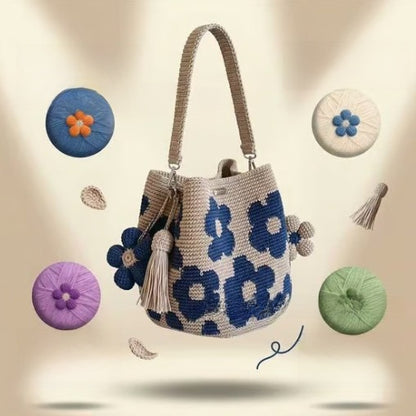 Blue floral crochet cotton bucket bag with a tassel charm and yarn balls on a soft background