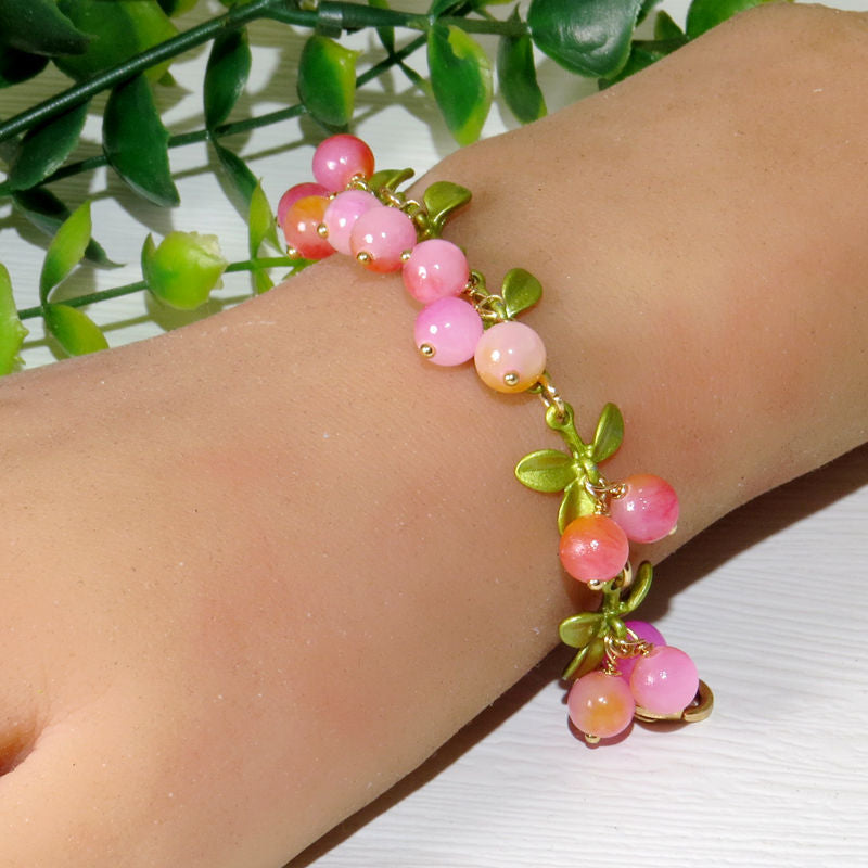 Lapis lazuli blue bead clusters with green leaves along a gold tone chain bracelet