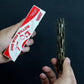 Hand holding the red and white One Wish Willow box beside the dark twisted wand