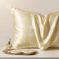 Yellow check silk pillowcase in pale gingham with a perfume bottle and sleep mask