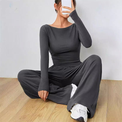 Dark gray long sleeve boat neck top and wide leg pants two piece set, worn seated on a wood floor