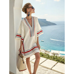 Loose V neck bohemian beach cover up dress in a blue and orange sun motif print, worn in the sea breeze at a resort