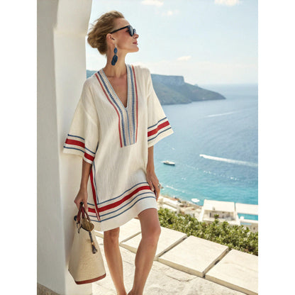 Loose V neck bohemian beach cover up dress in a blue and orange sun motif print, worn in the sea breeze at a resort
