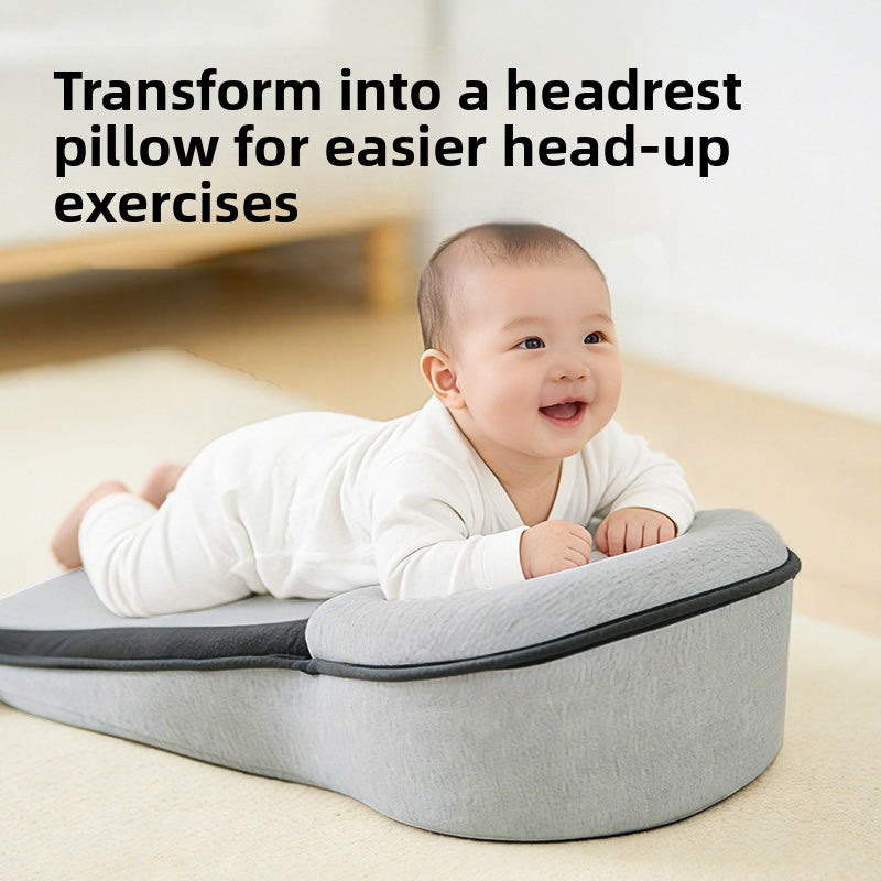 Baby lying on its tummy over the raised end of a grey wedge lounger pillow, with a text overlay