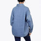 Back view of a washed light blue denim shirt with dropped shoulders and a rounded hem with a side slit