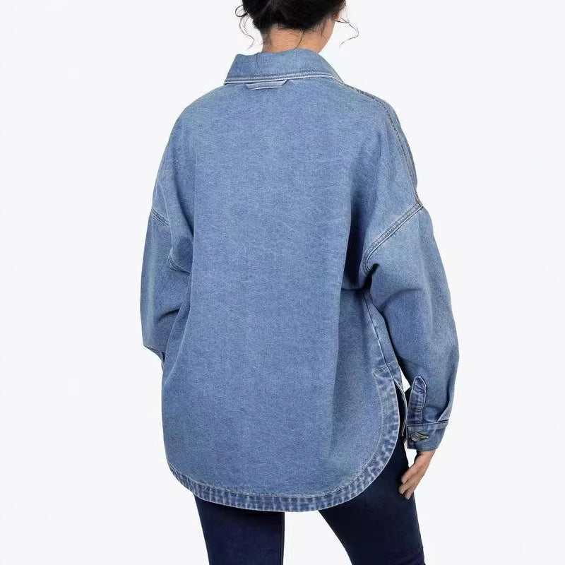 Back view of a washed light blue denim shirt with dropped shoulders and a rounded hem with a side slit