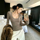 Taupe long sleeve scoop neck knit top on a model with white trousers, front view