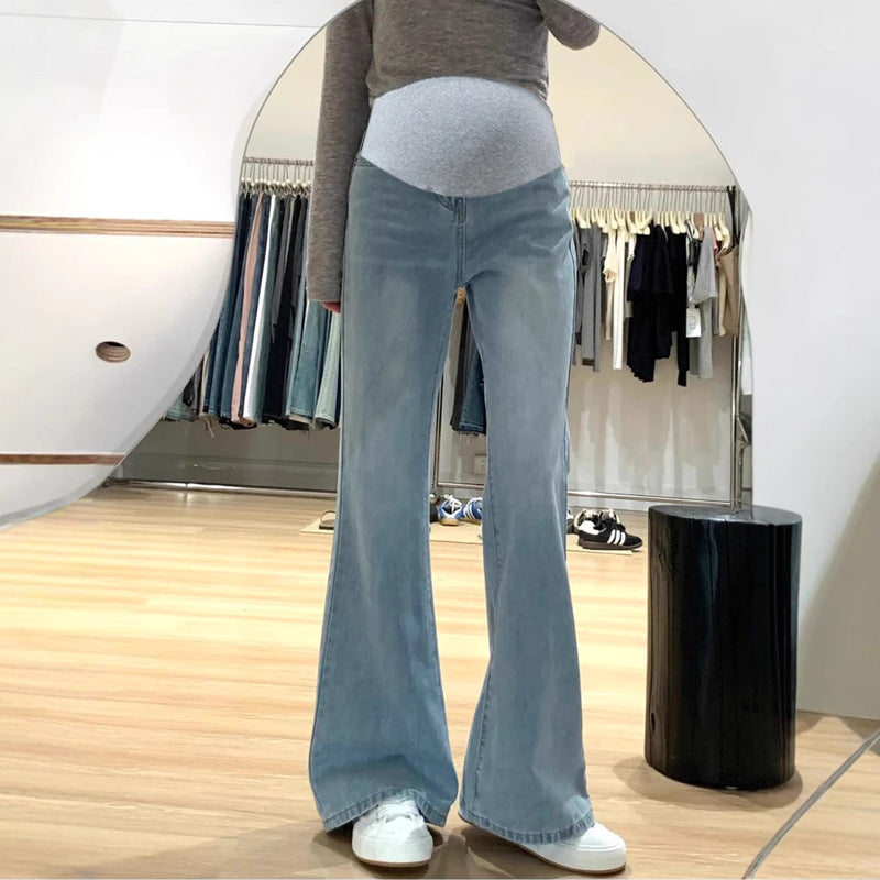 Light blue flared maternity jeans with a gray belly panel, worn with a gray top and white sneakers
