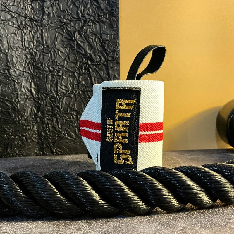 White and red elastic wrist wrap rolled up beside a heavy black training rope