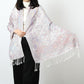 Woman in an ivory paisley jacquard scarf held open to show the pastel pink, blue and lilac pattern