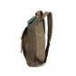 Side view of olive canvas backpack with brown shoulder strap and zip detail on the side panel