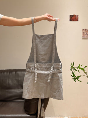 Gray washed suspender pinafore dress held up showing straps and front pockets