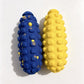 Blue and yellow bumpy corn cob shaped dog toys side by side on a white background, top view