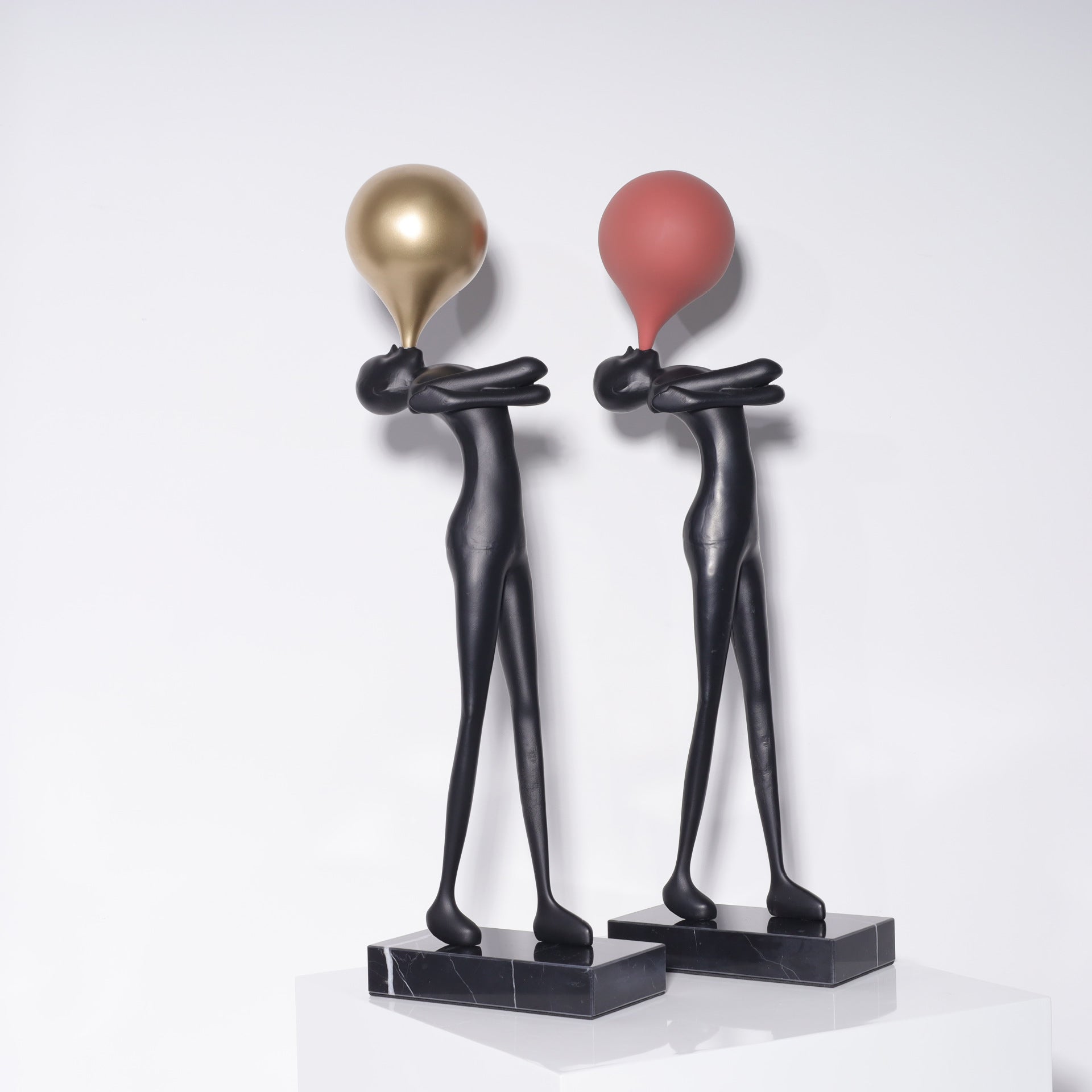 Balloon figure sculpture with a gold toned balloon above a matte black body on a veined marble base