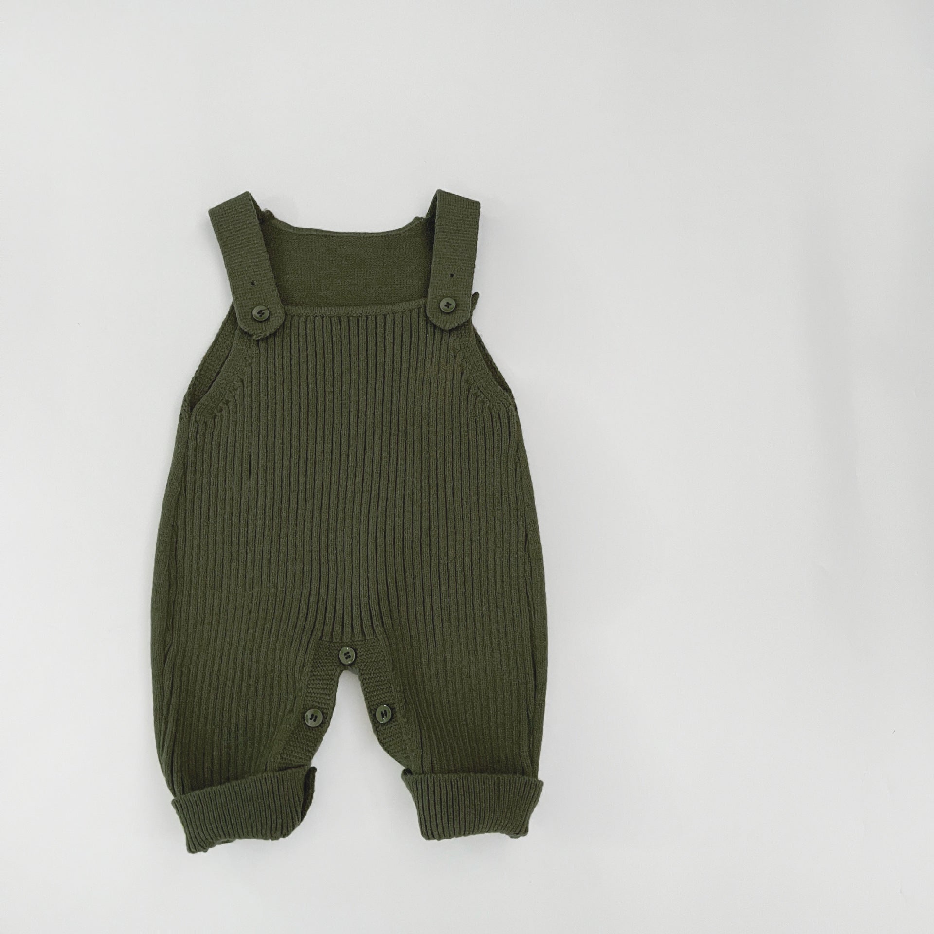 Knit baby dungarees layered into a styled lifestyle nursery setting