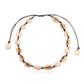 Cowrie shell choker on black knotted cord laid flat, sliding knot and shell tipped tails visible