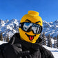 Yellow block head printed face cover with tongue out and ski goggles, thumb up in black ski gloves