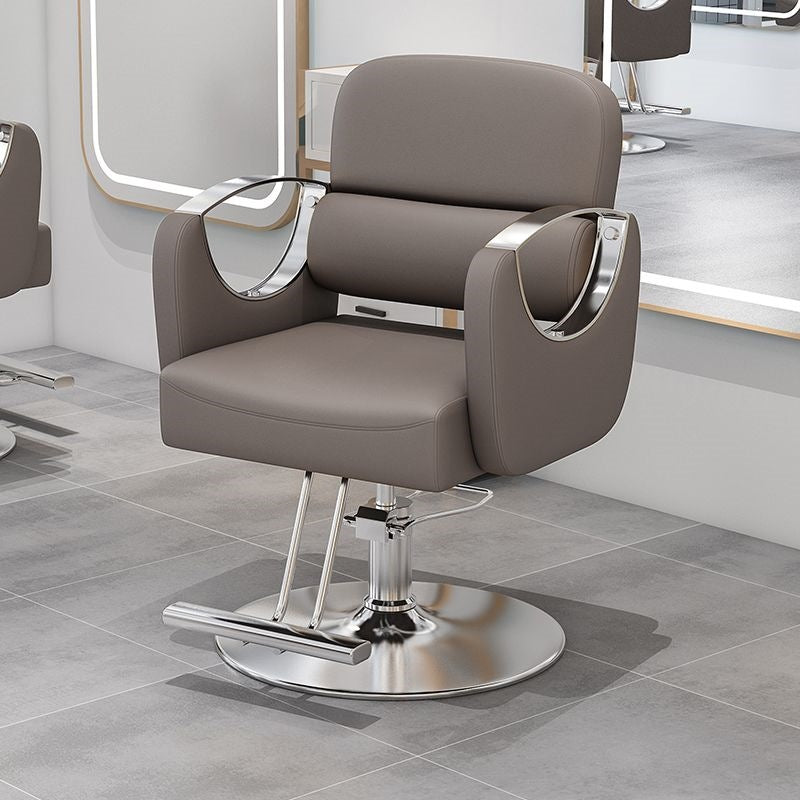 Light beige salon styling chair with silver metal armrests and a hydraulic column base